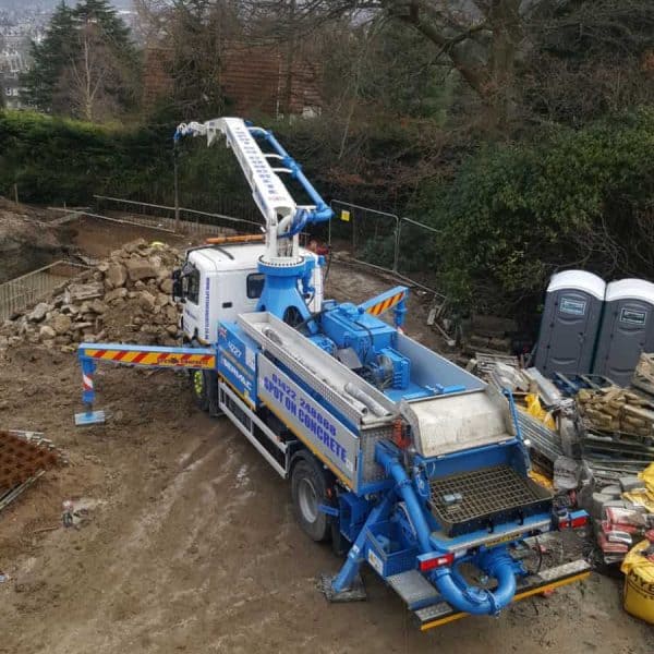 White blue and grey concrete pump hire machine on a construction site with top soil available from spot on concrete