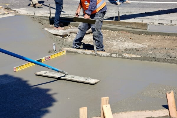 Construction worker pouring ready-mix concrete on a highway project, ensuring a smooth and durable road surface.